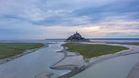 Le-Mont-Saint-Michel,-France-Castle-in-Ocean-Sunrise-Night-to-Day-Hyperlapse,-Aerial-forward