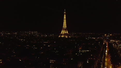 Torre-Eiffel-En-La-Noche.-Vuele-Sobre-El-Desarrollo-De-La-Ciudad-Y-La-Vista-Del-Punto-De-Referencia-Popular-Iluminado-En-El-Destino-Turístico.-París,-Francia