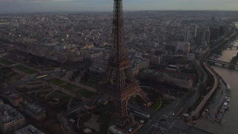 Fliegen-Sie-Um-Den-Eiffelturm-Herum.-Luftaufnahmen-Des-Stadtbezirks-Und-Des-Seine-Flusses,-Die-Den-Dämmerungshimmel-Reflektieren.-Paris,-Frankreich