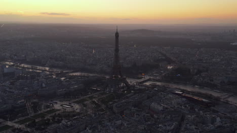 Slide-and-pan-shot-of-Eiffel-Tower.-Aerial-panoramic-footage-of-large-city-at-dusk,-colourful-twilight-sky-in-background.-Paris,-France