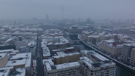 Los-Reenviadores-Vuelan-Sobre-La-Ciudad-En-Invierno.-Varios-Edificios-Alrededor-Del-Río-Con-Techos-Blancos-Cubiertos-De-Nieve.-Vista-Nebulosa-De-Berliner-Dom-Y-Fernsehturm.-Berlín,-Alemania