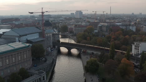 S-Bahn-train-crossing-Spree-river-on-railway-bridge-heading-to-Museum-island.-Forward-flying-above-river.-Berlin,-Germany.