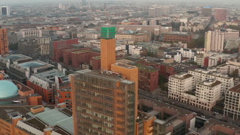 Dia--Und-Schwenkaufnahmen-Der-Spitze-Eines-Modernen-Geschäftsgebäudes,-Das-über-Der-Entwicklung-In-Der-Stadt-Thront.-Berlin,-Deutschland
