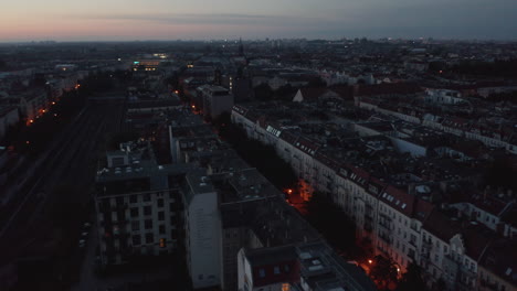 Fly-above-blocks-of-residential-buildings.-Tilt-up-reveal-view-of-city-before-sunrise.-Colourful-twilight-sky.-Berlin,-Germany