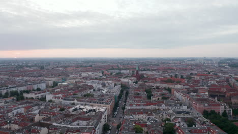 Forwards-fly-above-large-city-in-sunrise-time.-Tilt-down-footage-of-buildings-and-streets-in-urban-neighbourhood.-Berlin,-Germany