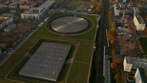 Establishing-Aerial-Shot-above-Futuristic-Velodrome-Building-cycling-Arena-in-Berlin,-Germany,-Aerial-tilt-up-view-at-Sunset