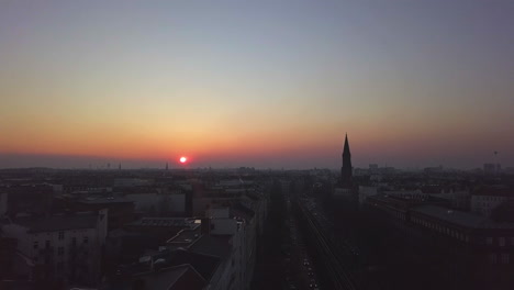 Above-elevated-Subway-Railroad-tracks-in-Berlin-at-Dusk-with-Sunset-Cityscape,-Aerial-forward-Dolly-in