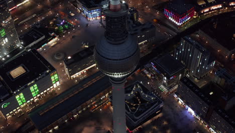 El-Famoso-Rascacielos-De-La-Torre-De-Televisión-De-Berlín-Sobre-El-Paisaje-Urbano-Por-La-Noche-Con-Luces-De-Colores-En-La-Capital-Alemana,-Toma-Aérea-Amplia-Que-Establece-Un-Tiro-Al-Revés