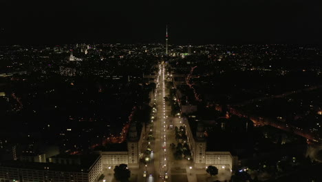 Rising-up-over-Berlin,-Germany-Cityscape-at-night-with-Empty-Karl-Marx-Allee-Frankfurter-Tor-at-Night-with-No-People-in-Berlin,-Germany-during-Coronavirus-Lockdown