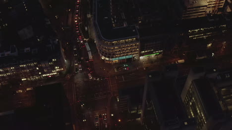 AERIAL:-Beautiful-Overhead-Shot-of-busy-intersection-at-night-with-Car-traffic-and-city-lights
