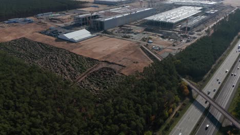 Huge-Construction-Site-Building-Site-next-to-German-Highway-Autobahn,-Tesla-Gigafactory-near-Berlin-Brandenburg,-Germany,-Aerial-Wide-View