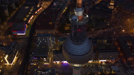 Orbit-shot-around-top-of-Fernsehturm-TV-tower.-Night-hyperlapse-of-city-streets,-cars-driving-on-roads-bellow.-Berlin,-Germany