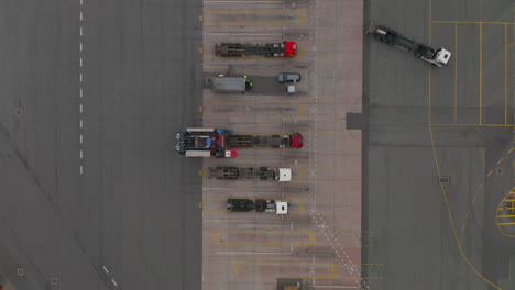 Overhead-top-down-aerial-view-of-a-forklift-moving-cargo-from-parked-truck-in-cargo-terminal-seaport