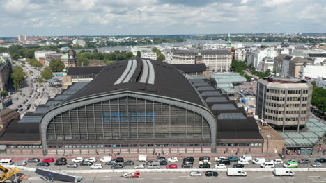 Volar-Alrededor-De-Hamburgo-Hauptbahnhof.-Vista-Aérea-De-Un-Gran-Edificio-Histórico,-Terminal-De-Transporte-Ocupado-Y-Tráfico-En-Las-Calles-Al-Lado.-Ciudad-Libre-Y-Hanseática-De-Hamburgo,-Alemania
