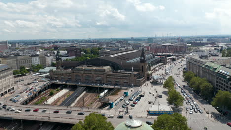 Fly-around-historic-building-of-Hamburg-Hauptbahnhof.-Aerial-view-of-large-busy-train-station-and-heavy-traffic-in-streets-around.-Free-and-Hanseatic-City-of-Hamburg,-Germany
