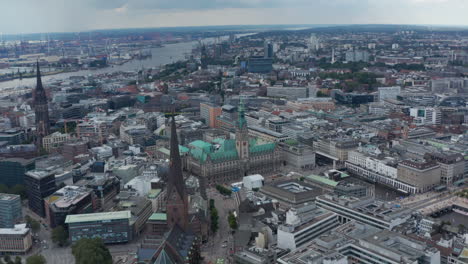 Aerial-view-of-historic-city-centre-with-city-hall-and-church-towers.-Docks-with-cranes-in-background.-Free-and-Hanseatic-City-of-Hamburg,-Germany