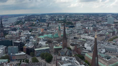 Aerial-view-of-historic-city-centre-with-tall-towers-of-city-hall-and-churches.-Harbour-cranes-in-background.-Free-and-Hanseatic-City-of-Hamburg,-Germany