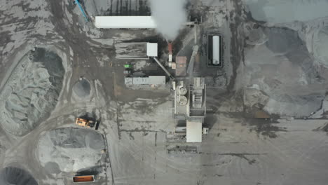 Top-down-drone-view-flying-over-an-asphalt-industry.-Overhead-view-showing-machinery,-establishment-and-pile-of-raw-material