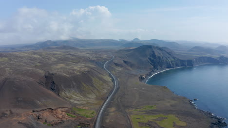 Aerial-view-reverse-of-amazing-coastline-of-iceland-with-volcanic-black-sand-beach.-Drone-view-flying-over-Ring-Road,-Route-n°1-that-runs-all-around-the-island