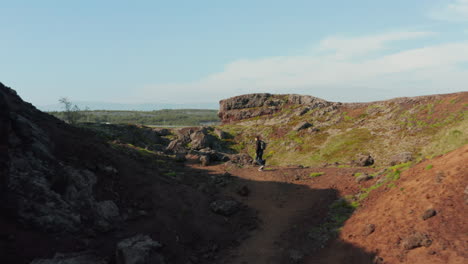 Vista-Aérea-De-Drones-Volando-Hacia-El-Hombre-Caminante-Solo-Caminando-En-Formaciones-Rocosas-Del-Desierto-En-Islandia.-Explorador-Masculino-De-Ojo-De-Pájaro-Disfrutando-De-Un-Panorama-Increíble-Y-La-Belleza-De-La-Naturaleza-De-Pie-Sobre-Un-Acantilado-De-Piedra