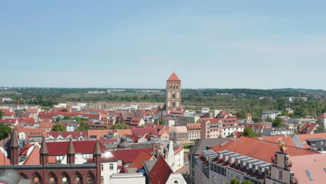 Forwards-fly-above-city-hall-towards-old-tower-of-Nikolaikirche-church.-Aerial-view-of-various-building-with-tiled-roofs