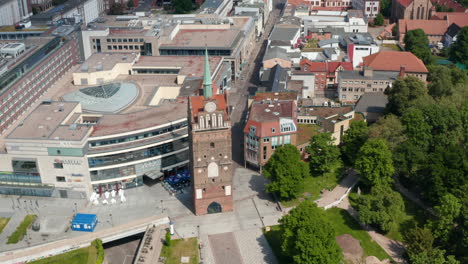 Aerial-view-of-historic-town-gate-Kropeliner-Tor-next-to-modern-building-of-shopping-centre.-Tilt-up-reveal-of-city-centre