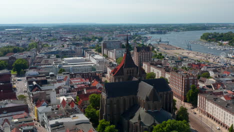 Backwards-fly-above-city.-Large-brick-gothic-style-religious-building-of-Saint-Marys-church.-Panoramic-aerial-view-of-historic-city-centre