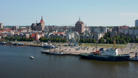 Slide-and-pan-footage-of-ships-at-waterfront-in-city.-Various-town-buildings-in-background