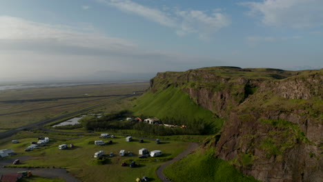 Drone-view-of-amazing-green-countryside-in-Iceland.-Aerial-view-drone-flying-over-stunning-icelandic-landscape-with-caravan-and-touristic-camper-traveller.-Amazing-in-nature-travel-destination