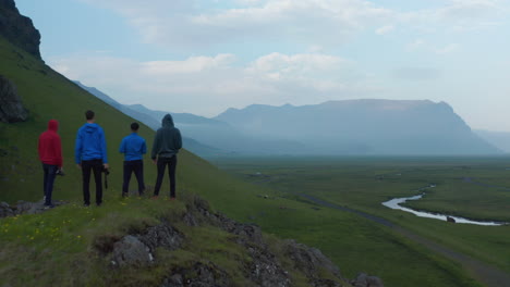 Vista-De-Pájaro-De-Drones-Cuatro-Personas-De-Pie-En-La-Cima-De-Las-Tierras-Altas-De-Islandia-Mirando-Un-Panorama-Impresionante.-Vista-Aérea-Paisaje-Brumoso-Y-Brumoso-Del-Campo-Del-Sur-De-Islandia-Con-Groenlandia-Y-Montañas