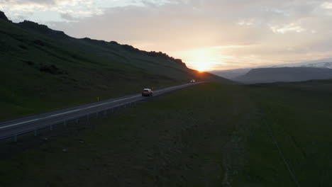 Aerial-view-of-ring-road-in-Iceland-with-fast-driving-car-at-sunset.-Top-view-from-drone-of-highway-car-peacefully-driving-in-golden-hour-in-evening