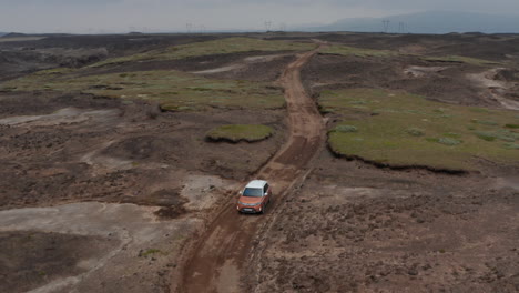 Aerial-view-tracking-car-moving-on-wild-road-in-Iceland.-Forward-flight-on-surreal-icelandic-landscape.-Adventure-roadtrip-of-a-car-offroad