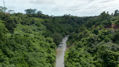 Aerial-dolly-shot-of-a-fast-flowing-jungle-river-flowing-through-the-canyon-in-a-tropical-rainforest-in-Bali