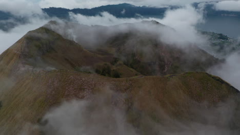 Close-up-aerial-view-of-the-top-of-the-mountain-ridge-on-active-volcano-mount-Batur-surrounded-by-fog