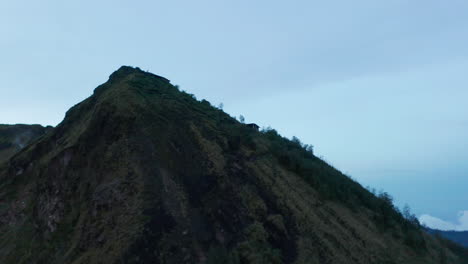 Aufsteigende-Luftaufnahme,-Die-Im-Dunkeln-An-Einem-Tropischen-Hügel-Des-Mount-Batur-Vorbeifliegt