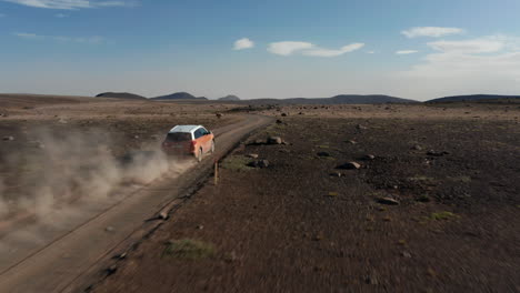 Birds-eye-view-vehicle-driving-in-dusty-highlands-in-Iceland-countryside-speeding-offroad.-Commercial-and-insurance.-Aerial-view-on-4x4-vehicle-on-icelandic-desert-road-travelling