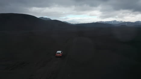 High-angle-view-4x4-vehicle-driving-on-black-desert-terrain-in-Icelandic-countryside.-Top-view-Skaftafell-national-park-with-black-volcanic-hills-highlands.-Amazing-in-nature.-Exploring-wilderness