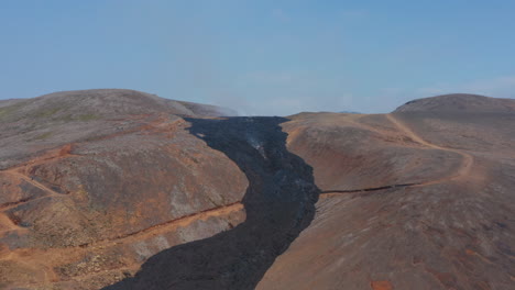 Aerial-drone-flying-forward-to-Fagradalsfjall-black-lava-river,-Iceland,-sunny-day