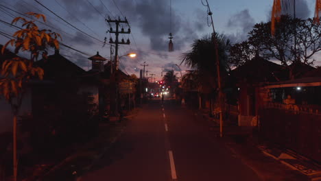 Motorcycles-driving-on-a-dark-street-in-Bali,-Indonesia.-Urban-street-city-traffic-after-sunset-in-Asia