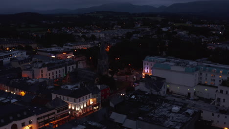 Aerial-shot-of-medieval-church-in-town-centre.-Illuminated-colour-houses-facades-in-evening.-Killarney,-Ireland