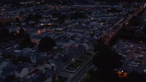 Fly-above-urban-neighbourhood-after-sunset.-residential-buildings-along-straight-street.-Killarney,-Ireland