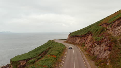 Forwards-tracking-of-car-driving-on-road-winding-along-sea-coast.-Panoramic-route-above-shore.-Ireland
