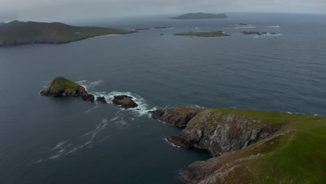 Aerial-panoramic-footage-of-islands-in-sea-near-coast.-Green-grass-with-rocky-cliffs-on-Dunmore-Head-promontory.-Ireland