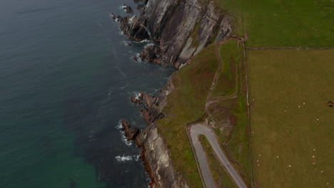 Blick-Aus-Der-Vogelperspektive-Auf-Menschen,-Die-Auf-Dem-Wanderweg-Entlang-Der-Küste-Auf-Dem-Dunmore-Head-Promontory-Spazieren-Gehen.-Grüne-Weiden-Und-Steile-Felsklippen.-Irland