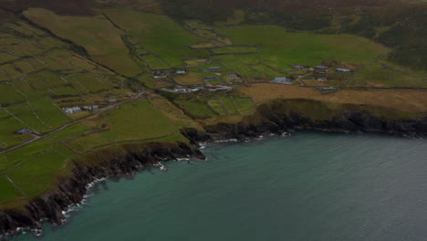 Aerial-panoramic-footage-of-coastal-landscape.-Detached-houses-surrounded-by-green-grass-pastures-in-countryside.-Ireland