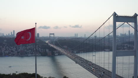 Dolly-forward-past-waving-Turkish-Flag-revealing-Bosphorus-Bridge,-Aerial-Wide-Shot-dolly-forward