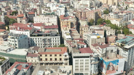 City-Streets-of-Istanbul-Tilt-up-to-reveal-Galata-Tower-in-Taksim-on-Sunny-Day,-Aerial-wide-establishing-shot