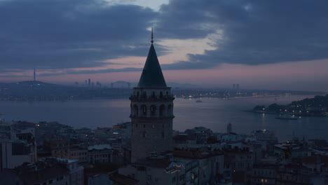 Galata-Tower-Silhouette-at-Blue-Hour-with-Bosphorus-in-Background-and-Red-Purple-Sky,-Aerial-slide-left