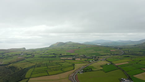 Aerial-panoramic-footage-of-agricultural-landscape-at-seaside.-Road-passing-through-countryside-with-green-fields-and-meadows.-Ireland
