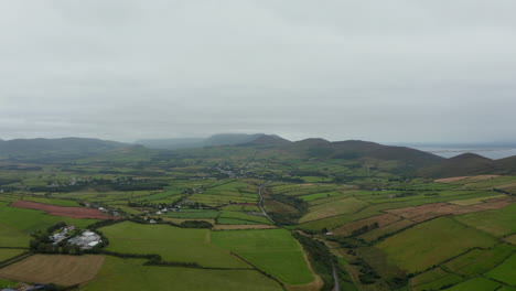 Toma-Aérea-De-Campos-Verdes-Y-Prados-En-El-Campo-En-Un-Día-Nublado.-Panorama-Del-Paisaje-Con-Colinas-En-El-Fondo.-Irlanda
